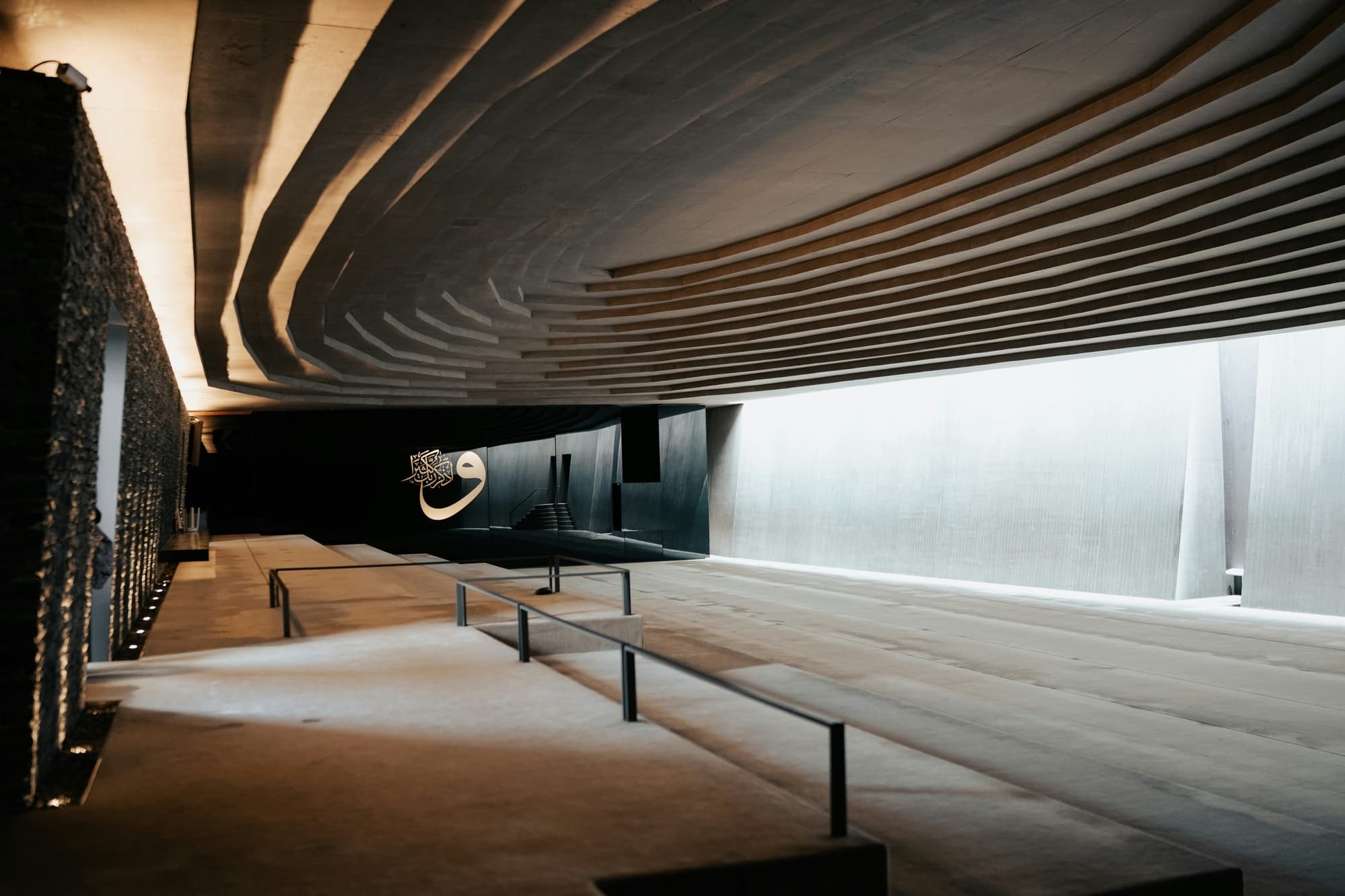 A ribbed soffit over a stone-walled hall, lit from below